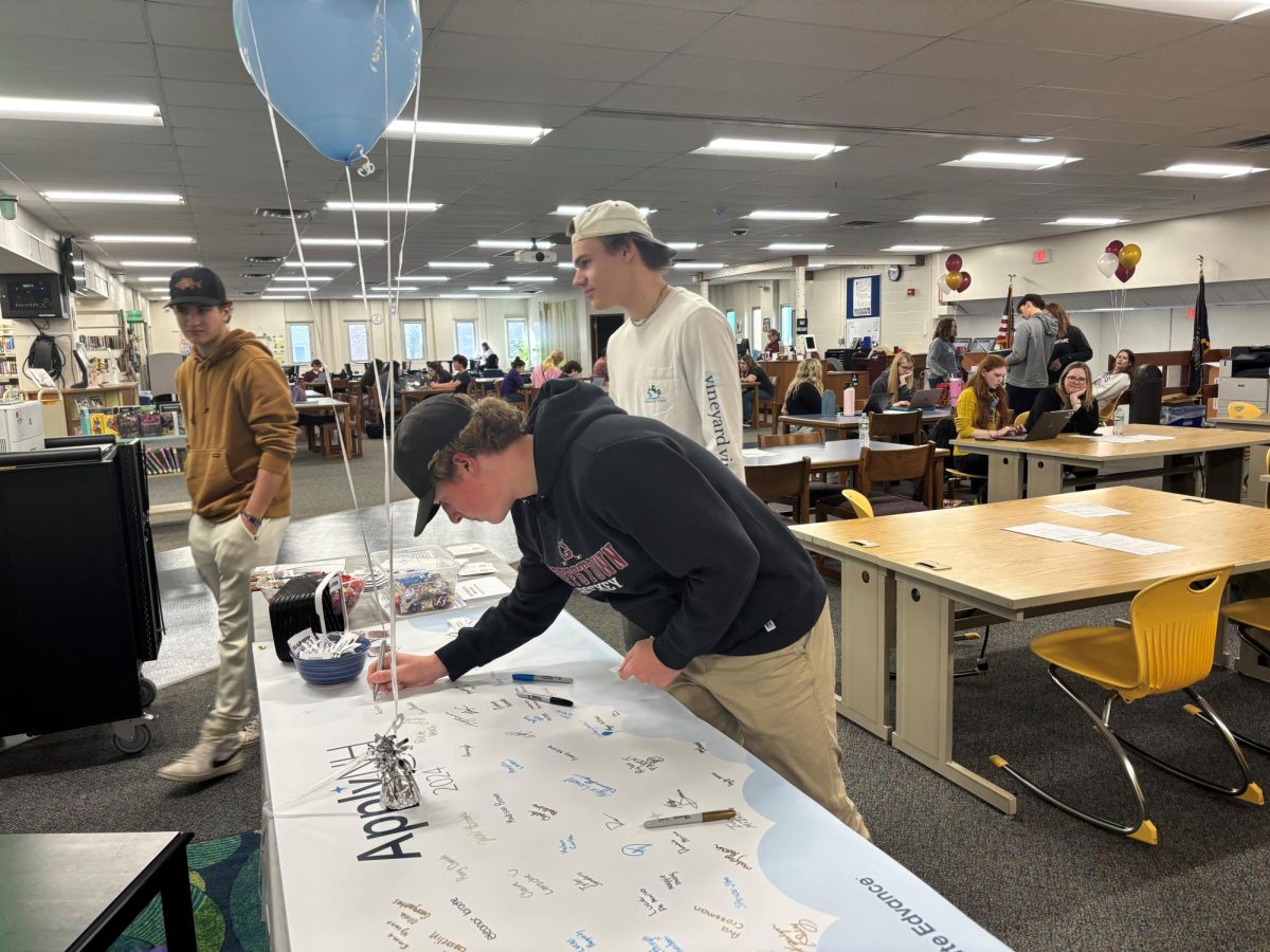 Senior, Austin Campbell signs Apply NH banner after clicking submit.